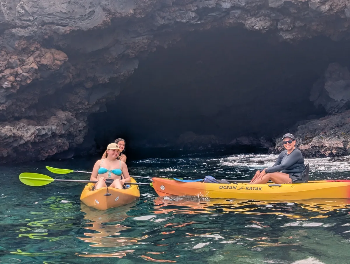 Two kayaks at the mouth of the sea cave over clear turquoise water