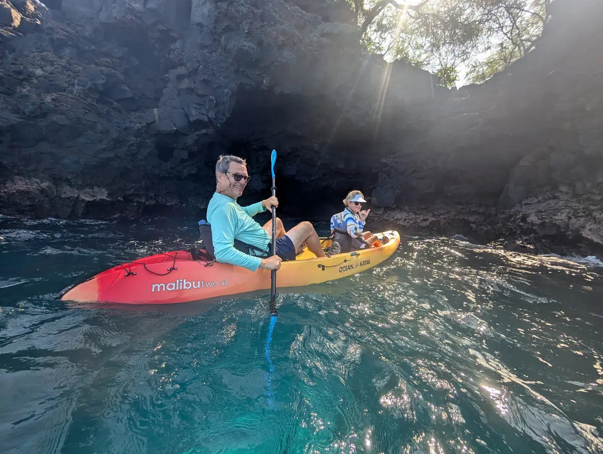 A father and son paddling inside the sea cave under a skylight